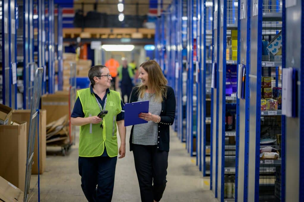 Two employees walking through a warehouse as part of an ERP system examples workflow.